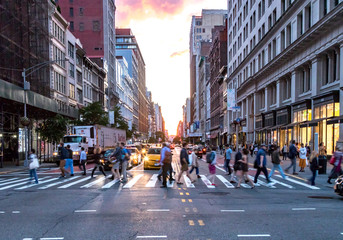 NEW YORK CITY - JUNE, 2018: Crowds of diverse people cross the busy intersection on 23rd Street and 5th Avenue in Manhattan with rush hour traffic in the background.
