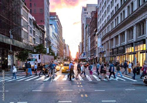 NEW YORK CITY - JUNE, 2018: Crowds of diverse people cross the busy intersection on 23rd Street and 5th Avenue in Manhattan with rush hour traffic in the background.