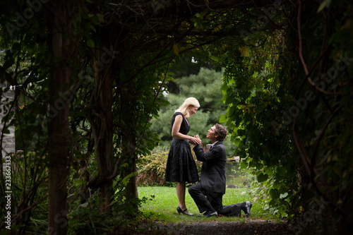 Man proposing to woman on grassy field