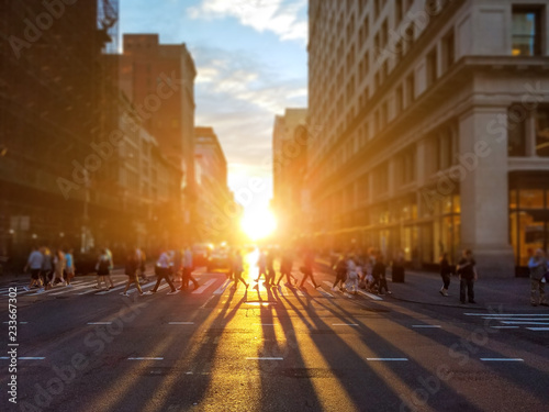 People cross busy intersection on 23rd Street in Manhattan New York City with the colorful light of sunset casting long shadows © deberarr