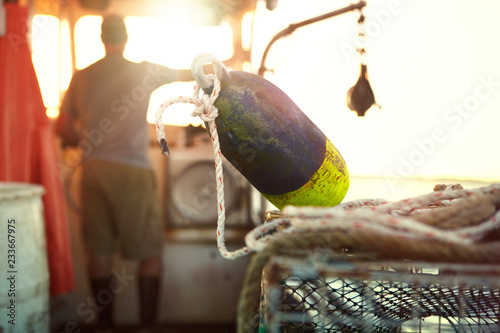 Фотография Fisherman sailing trawler with buoy on lobster trap
