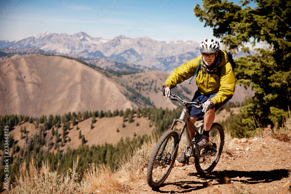 Fototapeta premium Confident hiker riding bicycle on mountain