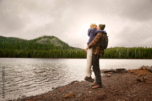 Photography Side view of couple kissing while standing at lakeshore against sky