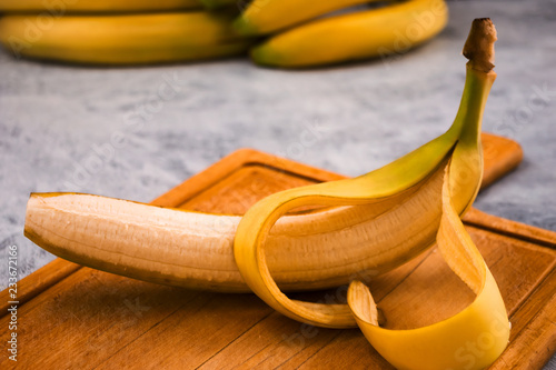 Ripe banana with cut yellow peel on wooden background.