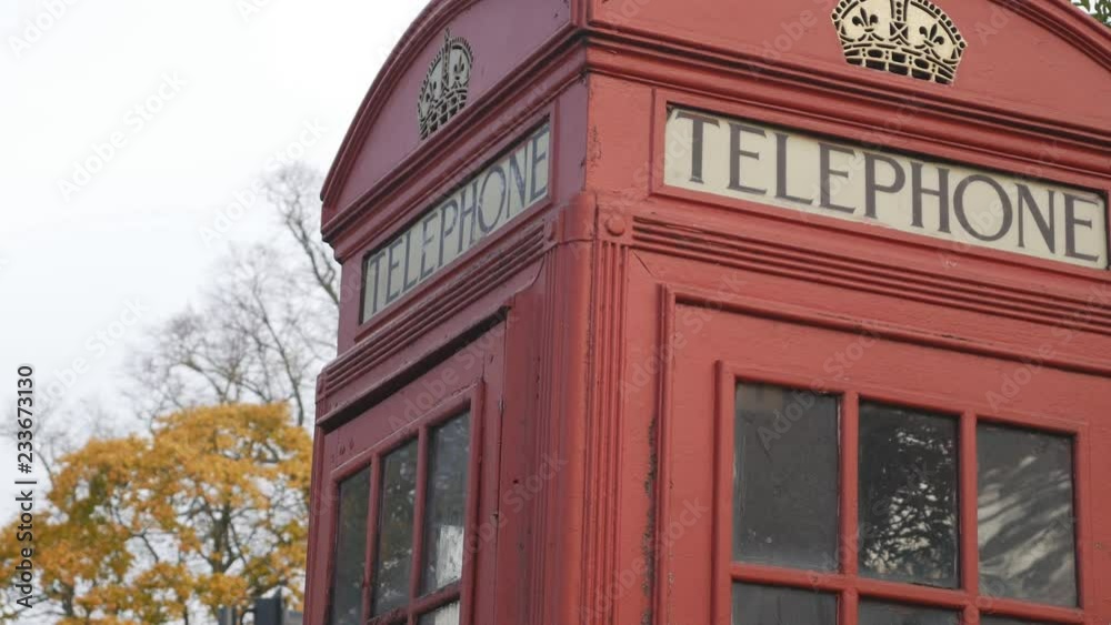 A red telephone booth in autumn. A red telephone booth in autumn.