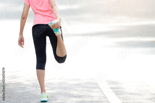 body beautiful of woman running on road in the park which runner athletic by running shoes and she was stretching her thigh muscles. Health and sport concept background,