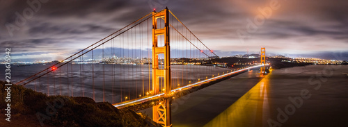 Panoramic night view of Golden Gate Bridge, San Francisco downtown area in the background, California