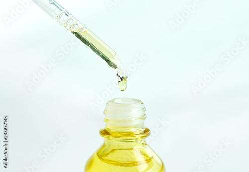 Dropping serum collagen moisturizer of face into clear yellow bottle soft light background. Protector skin Treatment facial essence oil, Vitamin C. Beauty and spa Concept. photo