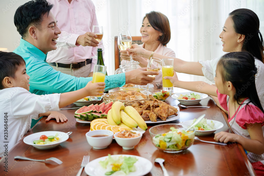 Happy Asian family toasting with glasses of juice and wine at dinner Happy Asian family toasting with glasses of juice and wine at dinner