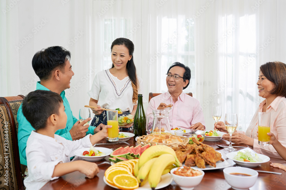 Happy big Asian family eating at talking at big dinner table