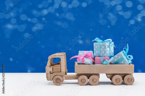 Wooden toy truck with gifts in boxes packed in elegant paper. 