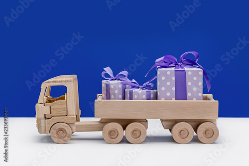 Wooden toy truck with gifts in boxes decorated with ribbons and bows.