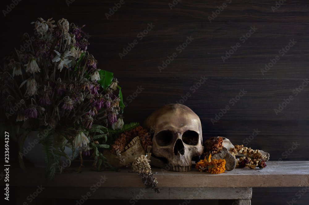 Skull with bone and withered flowers in the vase whis has old wreath on the plank Skull with bone and withered flowers in the vase whis has old wreath on the plank