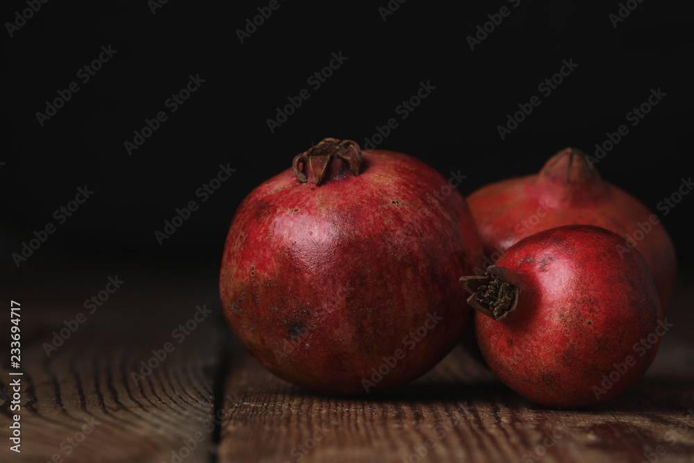 Beautiful composition with juicy pomegranates, on old wooden table