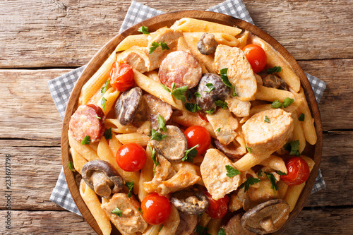 Cajun Chicken Pasta with Sausage mushrooms and tomatoes close-up on a plate. horizontal top view