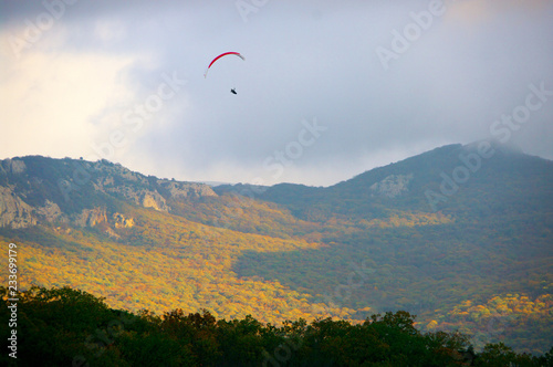 Paraglider over mountains at autumn day
