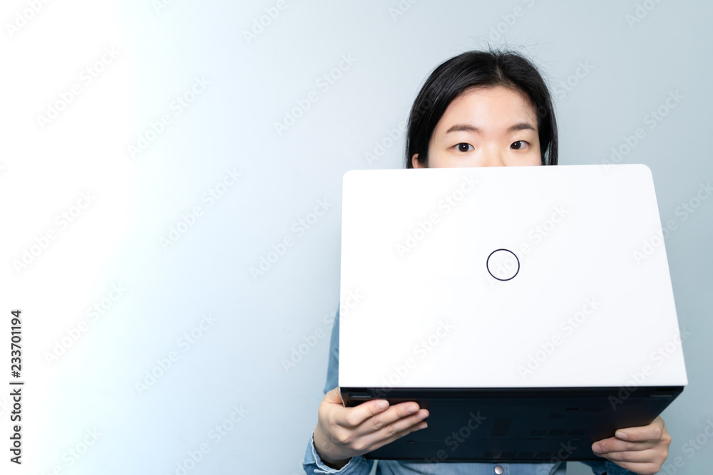 half of Asian business woman FACE, holding laptop over BLUE sky background with copy text space, Looking at camera. half of Asian business woman FACE, holding laptop over BLUE sky background with copy text space, Looking at camera.