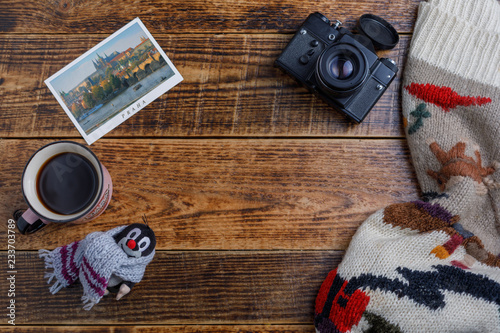 Accessories for travel on the background of wood, top view. Camera and postcard and Czech toy mole.