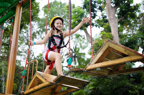 Child in adventure park. Kids climbing rope trail.