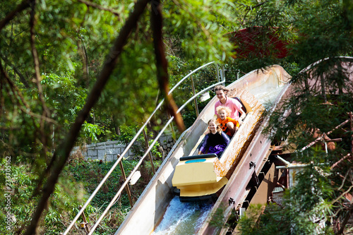 Family with kids on roller coaster in theme park.