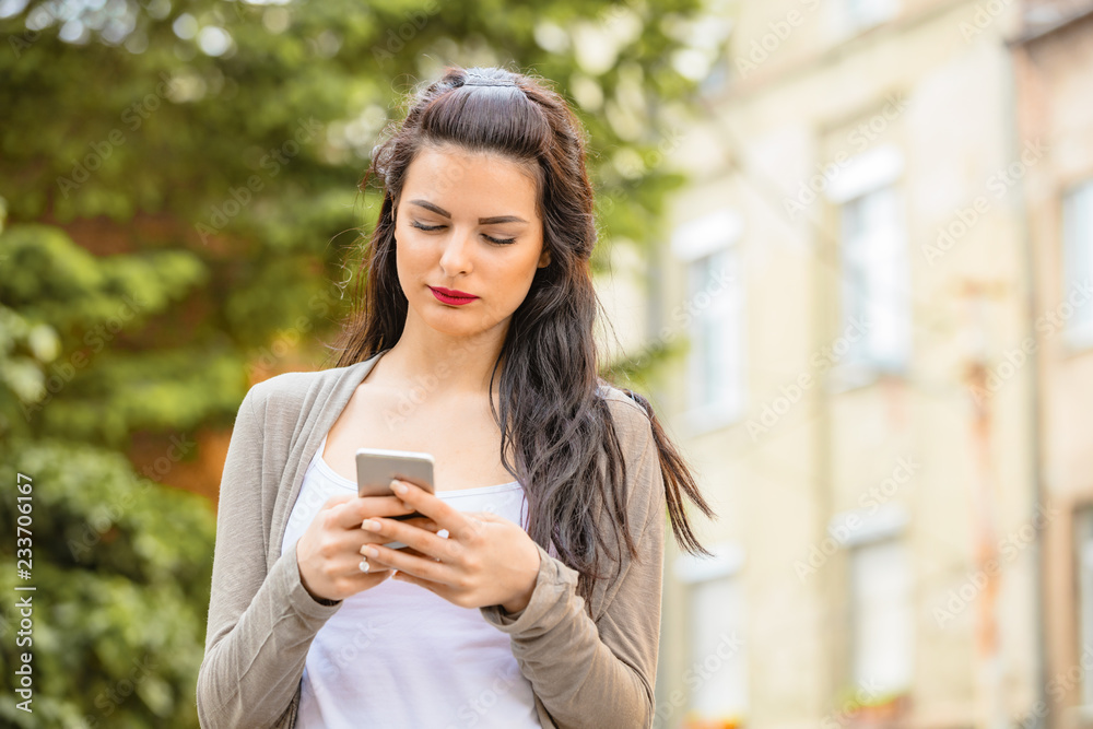Cute young woman using cellphone in urban surroundings. Cute young woman using cellphone in urban surroundings.