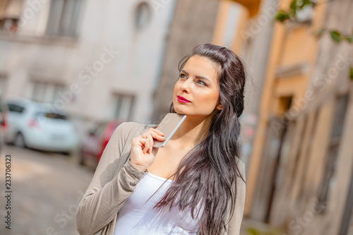 Cute young woman using cellphone in urban surroundings.