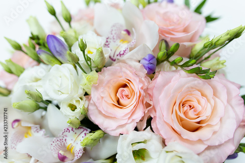 Delicate bouquet of white and pink roses and orchids with green leaves in a hat box of cerulean color on a light background