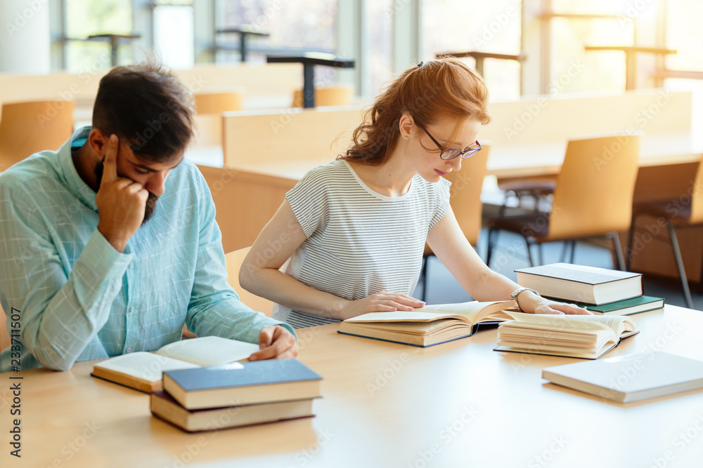 Young and beautiful students studying in library Young and beautiful students studying in library