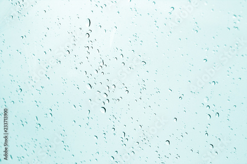 Blured water drops on window in cyan tone.
