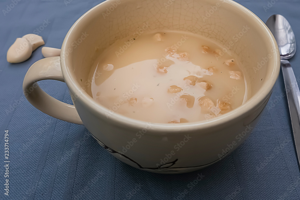 Chicken cream soup with croutons in a yellow cup on a gray background. Chicken cream soup with croutons in a yellow cup on a gray background.
