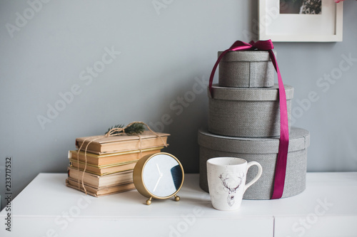 Stack of old vintage books. Books, craft present gift box and cup of tea or coffee cozy  scandinavian interior on gray background. 