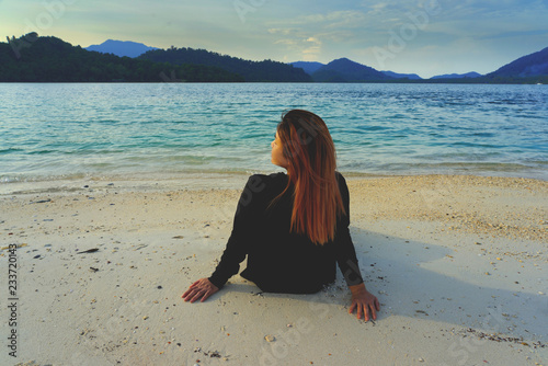 Back of Asian woman relaxing and sitting on sand beach