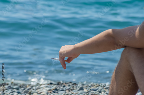 Male hand with a cigarette at the beach