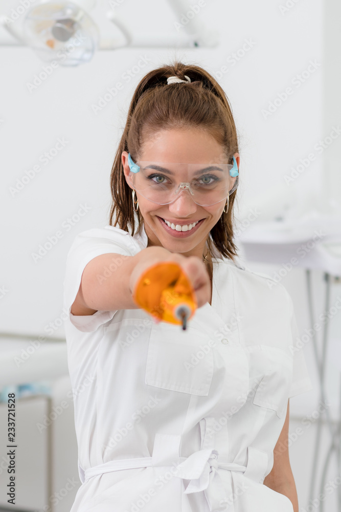 beautiful orthodontist girl posing with polymerization lamp in hand beautiful orthodontist girl posing with polymerization lamp in hand