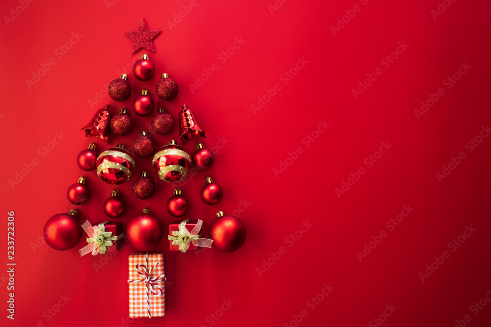 Christmas background concept. Top view of gift box with red ball and bell in shape of Christmas tree on red background. Christmas background concept. Top view of gift box with red ball and bell in shape of Christmas tree on red background.