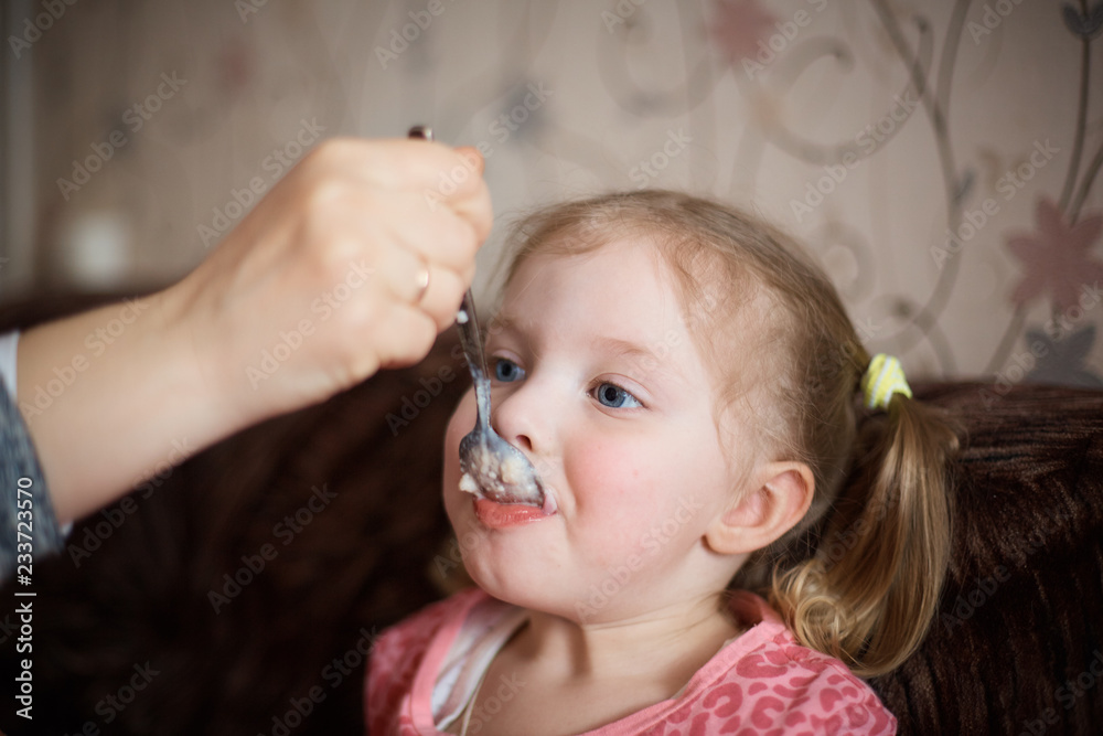 mom feeds her little daughter in the kitchen baby food mom feeds her little daughter in the kitchen baby food
