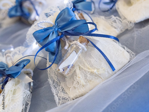 фотографія Wedding favor decorated with lace and blue ribbon with message in a bottle with