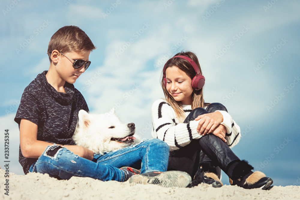 Happy 11 year old boy hugging his dog breed Samoyed at the seashore against a blue sky close up. Best friends rest and have fun on vacation, play in the sand Happy 11 year old boy hugging his dog breed Samoyed at the seashore against a blue sky close up. Best friends rest and have fun on vacation, play in the sand