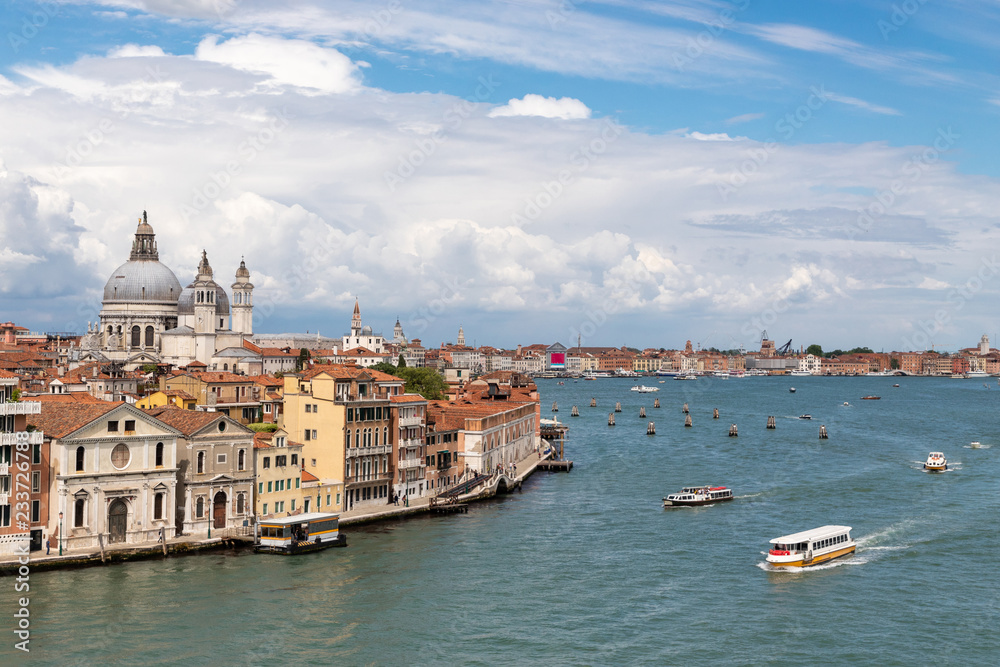 View of Venice from the sea. On the right side of the frame you can see the tourist ship. On the left side of the frame is the city. Blue sky with various clouds.