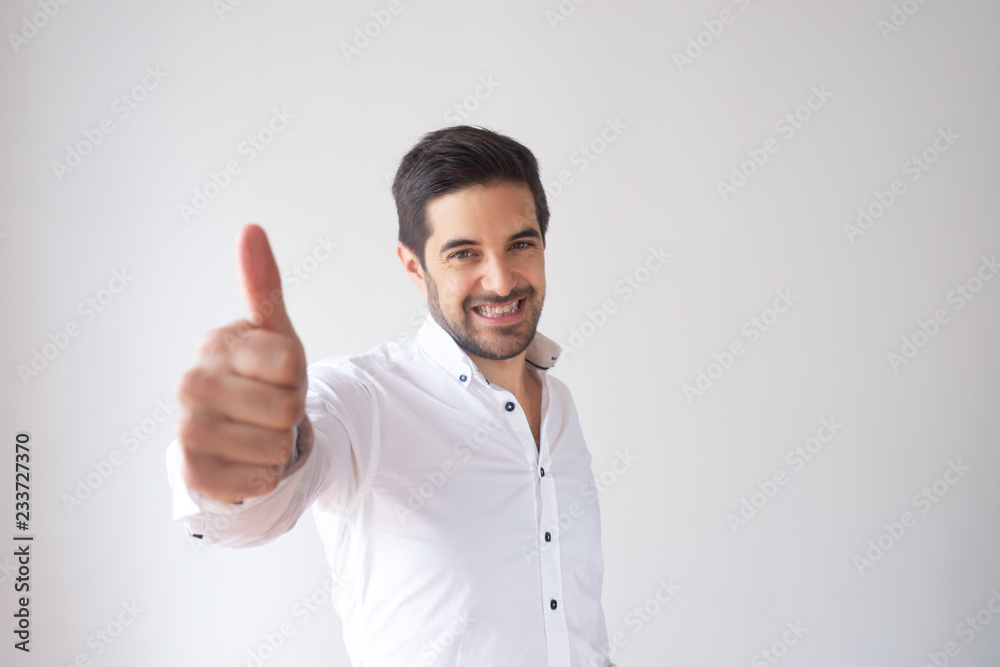 Successful young Caucasian businessman showing thumb up. Portrait of attractive man in white shirt praising your result with smile. Approval concept Successful young Caucasian businessman showing thumb up. Portrait of attractive man in white shirt praising your result with smile. Approval concept