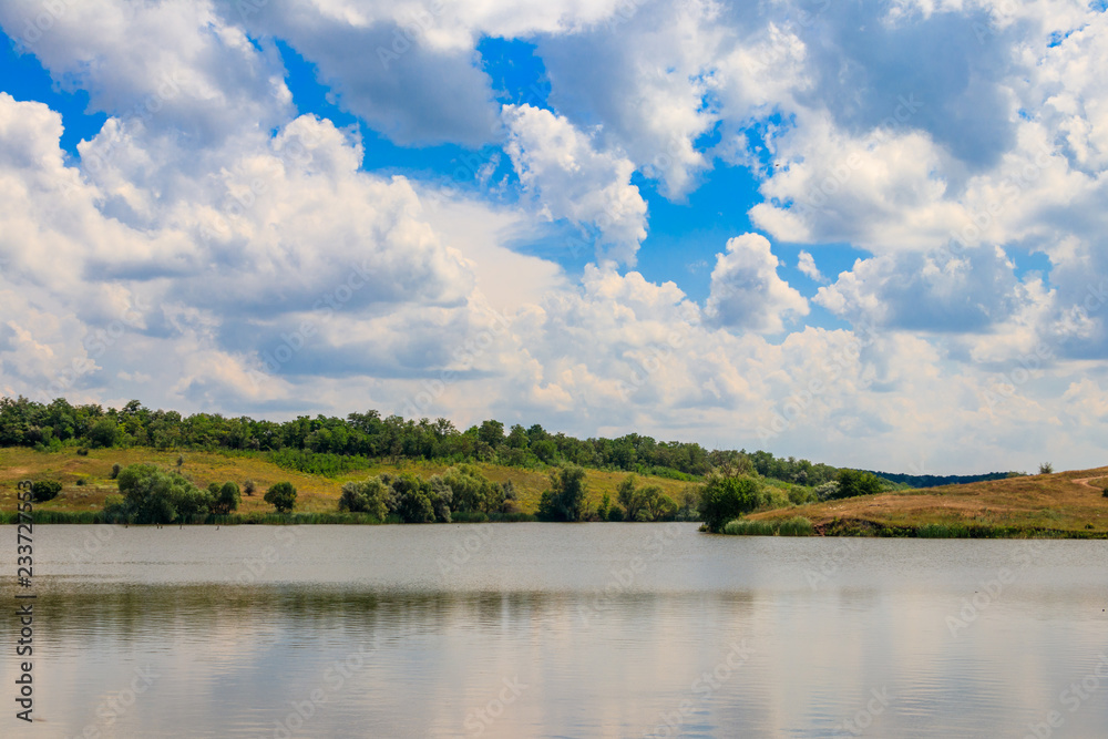 Summer landscape with beautiful lake, green meadows, hills, trees and blue sky Summer landscape with beautiful lake, green meadows, hills, trees and blue sky