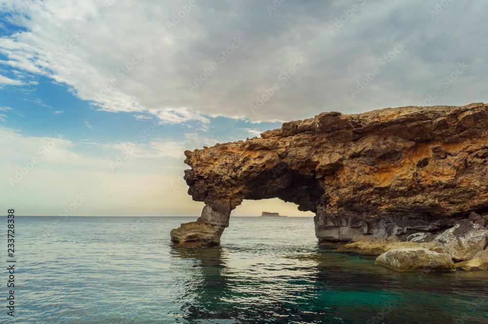 Natural arch. Filfla island under arch. Malta