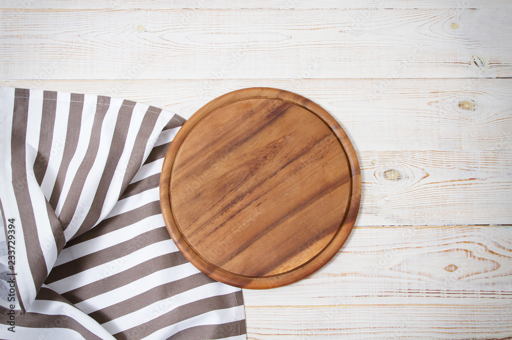 Round pizza cutting board and striped tablecloth on white wooden background. Top view. Copy space and mock up. Round pizza cutting board and striped tablecloth on white wooden background. Top view. Copy space and mock up.