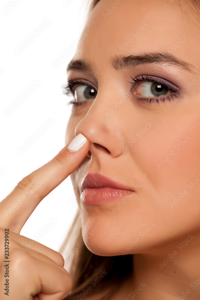 Portrait of beautiful woman checking her nose on white background