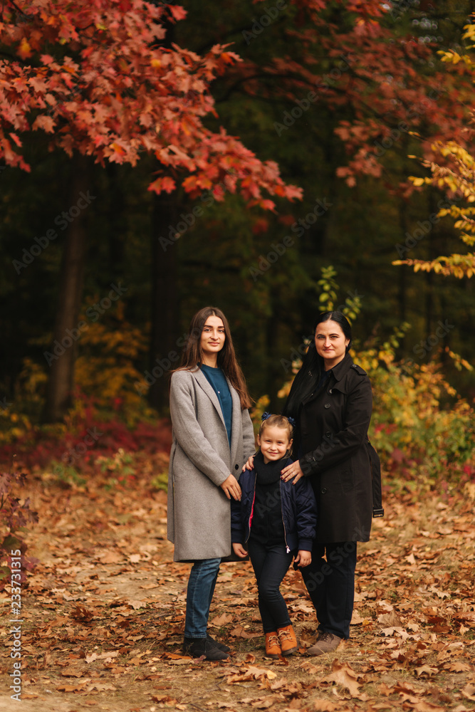 Portrait of happy family in autumn park. Mothe with two daughter. Two sister with mom Portrait of happy family in autumn park. Mothe with two daughter. Two sister with mom
