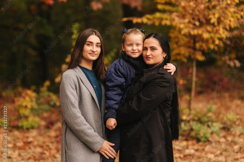 Portrait of happy family in autumn park. Mothe with two daughter. Two sister with mom Portrait of happy family in autumn park. Mothe with two daughter. Two sister with mom