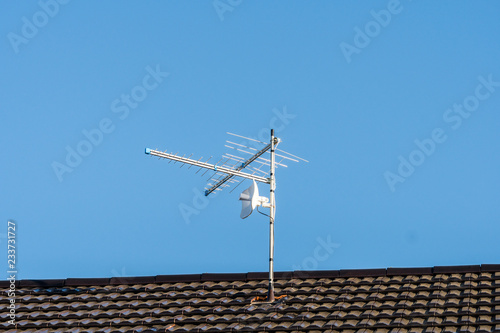 TV antenna on the house roof. Blue sky background.