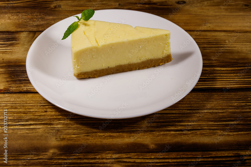 Piece of tasty sweet New York cheesecake in a white plate on wooden table