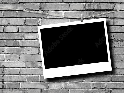 Blank rectangular instant photo frame against grey brick wall background