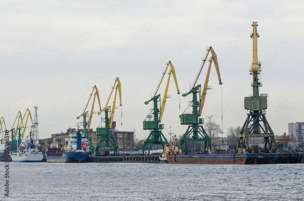 Sea port with cranes, ships at the pier for loading goods.
